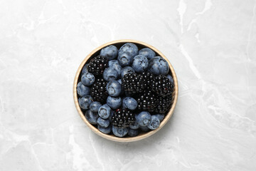 Blueberries and blackberries on light marble table, top view