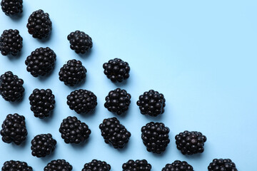 Tasty ripe blackberries on light blue background, flat lay. Space for text