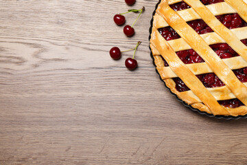 Delicious fresh pie and cherries on wooden table, flat lay. Space for text