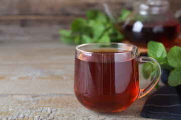 Cup with hot aromatic mint tea on wooden table. Space for text