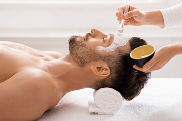 Obraz na płótnie Canvas Man getting face treatment at spa salon