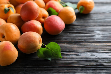 Many fresh ripe apricots on black wooden table. Space for text