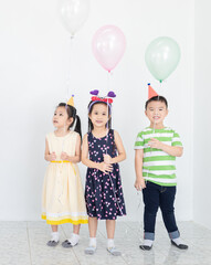 pretty asian children group standing and celebrate, they feeling happy in birthday party, they play together, they holding Helium balloon, Christmas and new years party