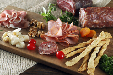 Cheese, parma ham, salami, sirloin, sausage with olives and spices on wooden board