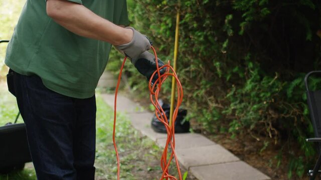 Senior gardener untangling a long wire for his lawnmower