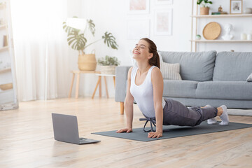 Positive yoga woman doing morning practice in front of laptop