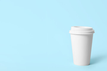 Takeaway paper coffee cup on light blue background. Space for text