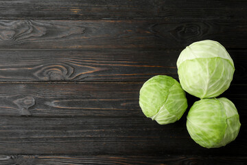 Ripe white cabbage on black wooden table, flat lay. Space for text - obrazy, fototapety, plakaty