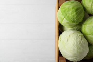 White cabbage in crate on wooden table, top view. Space for text