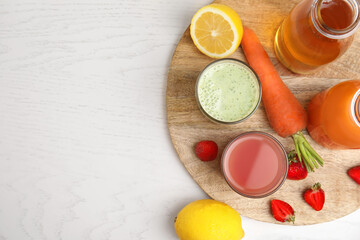 Different juices and fresh ingredients on white wooden table, flat lay. Space for text