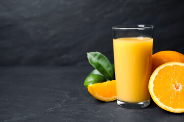 Fototapeta na wymiar Glass of orange juice and fresh fruits on grey table. Space for text