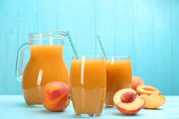Natural peach juice and fresh fruits on light blue wooden table