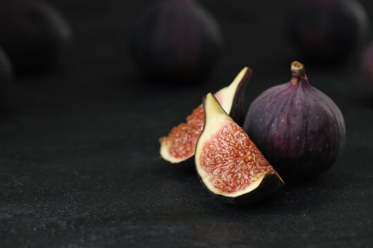 Tasty raw figs on black slate table, closeup. Space for text