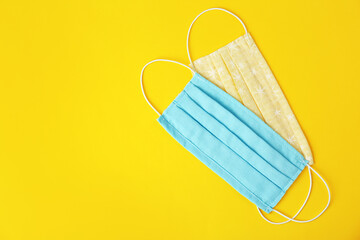 Homemade protective face masks on yellow background, flat lay. Space for text