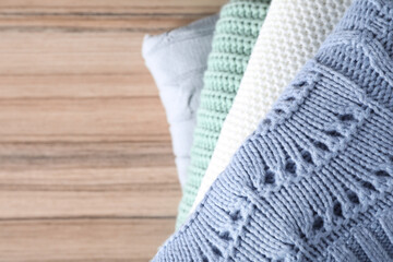 Stack of folded warm sweaters on wooden table, top view