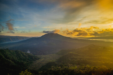 Beautiful mountain landscape during sunrise. Hills, Batur volcano and lake. Scenic panoramic view. Colorful sky with clouds. Foggy morning. Kintamani, Bali