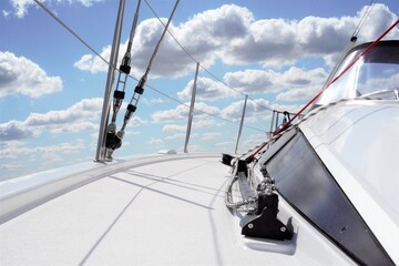 Sailing yacht, photographed from the front with blue sky and clouds in the background.