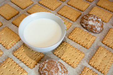 a cup full of milk and cookies, gingerbreads laid out in a diagonal pattern on an abstract light wooden background