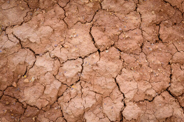 Close up image of brown dry soil texture. Abstract pattern of red-hot cracked clay. Lifeless desert background.