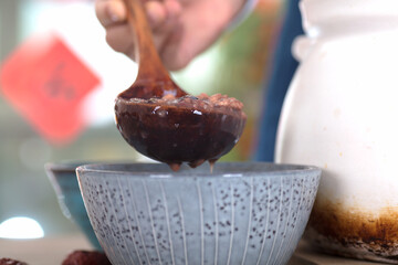 Close-up shot of Laba porridge filled into a bowl with a wooden spoon