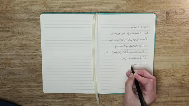 Woman writing Farsi in her to-do list 4K 60fps