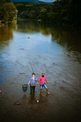 Portrait of cheerful two bearded men fishing. Fly fish hobby of men in checkered shirt. Relax on nature. Men bearded fishermen. Start living. Just do that only. Fishing on the lake.