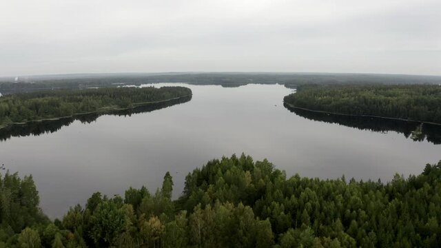 Relaxing drone shot of completely still lake in Sweden, camera slowly flying over the glassy water.