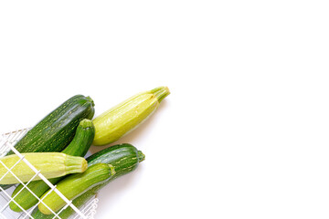 Autumn composition with vegetables. Whole ripe zucchini and eggplant are in a metal wicker basket on a white background. Autumn, Fall concept. Harvesting. Food ingredients. Copy space.