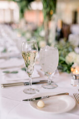 A champagne glass and a water glass at a wedding reception of an elegantly decorated table. 