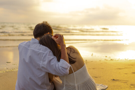 Couple in love watching sunset together on the beach travel summer holidays. People romance concept.