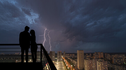 The romantic couple standing on the balcony on the rainy background