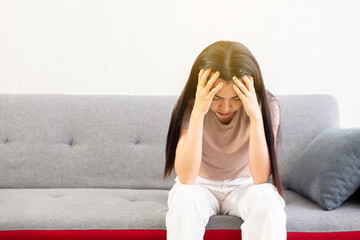 Depression asian woman have a headache or migraine of lonely sitting on sofa at home,Female under a...