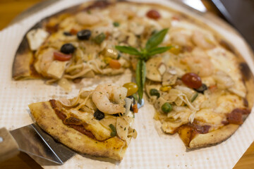 Delicious cheese stringy slice lifted of full supreme pizza baked fresh out of the oven.