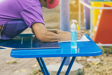 Blue alcohol gel bottle and a register book on the table for athletes to prevent Corona Virus (COVID -19) infection and spread before exercising in public park. New normal lifestyle. Selective focus
