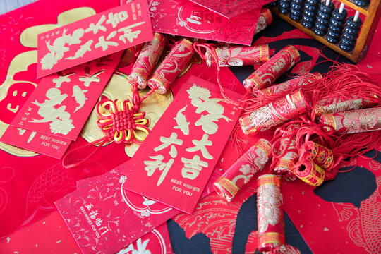 Red envelopes and firecracker ornaments scattered on red spring couplets background.The Chinese character on the red envelope means "great good luck"