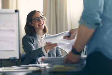 Happy businesswoman getting dokuments from male employee 