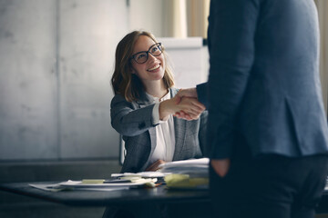 Happy businesswoman and businessman shaking hands at office 