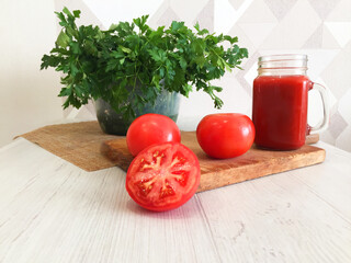 fresh vegetables, red tomato, juice on the table, tomato juice, orange juice, parsley, herbs, salad,  green tomatoes lie in a plate, tomatoes on a white background. 