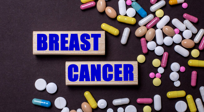 BREAST CANCER is written on wooden blocks near multi-colored pills. Medical concept