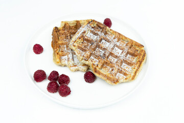 Traditional belgian waffles with raspberries on white plate