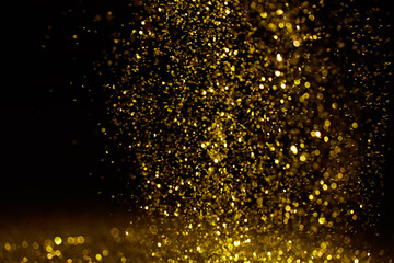 Sparkling golden glittering effect isolated on black background.