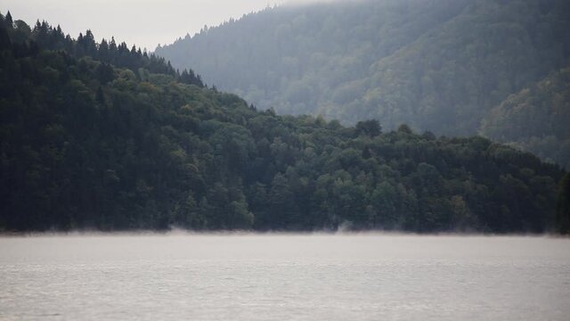 Static landscape in Carpathian Mountains in Romania at Bicaz lake wIth the fog steaming from the water