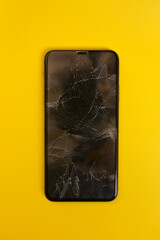 Broken smartphone screen on yellow background. Close up cracked phone.