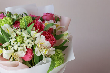 Pink-green bouquet of roses, white lilies, hydrangeas on a light background