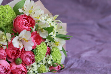 Pink-green bouquet of roses, white lilies, hydrangeas on a purple background