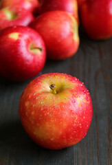 Closeup fresh ripe apples with water droplets isolated on black wooden table