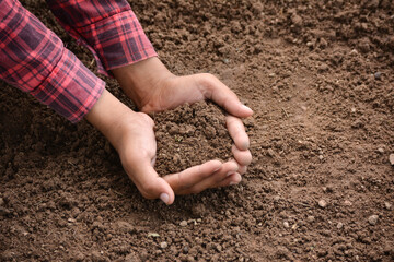 Hands holding soil in agricultural field