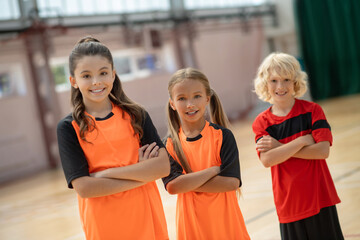 Three kids in bright sportswear standing with crossed arms