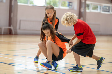 Kids in bright sportswear helping their friend in the gym