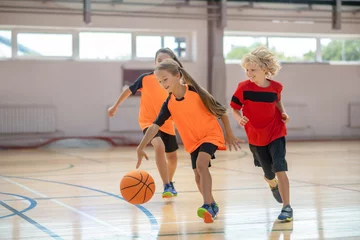 Gardinen Children in bright sportswear playing basketball and looking excited © zinkevych